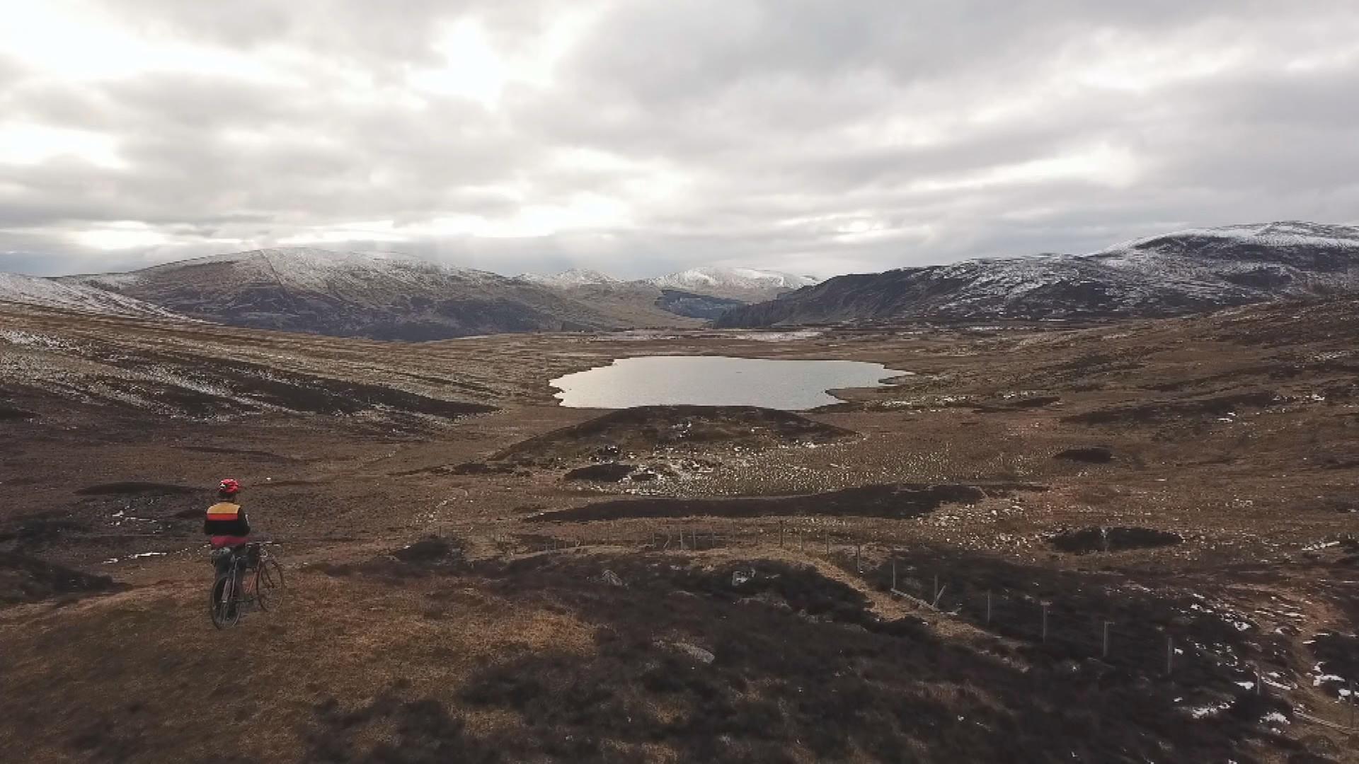 Eine Drohnenaufnahme der schottischen Highlands und Markus auf seinem Fahrrad.