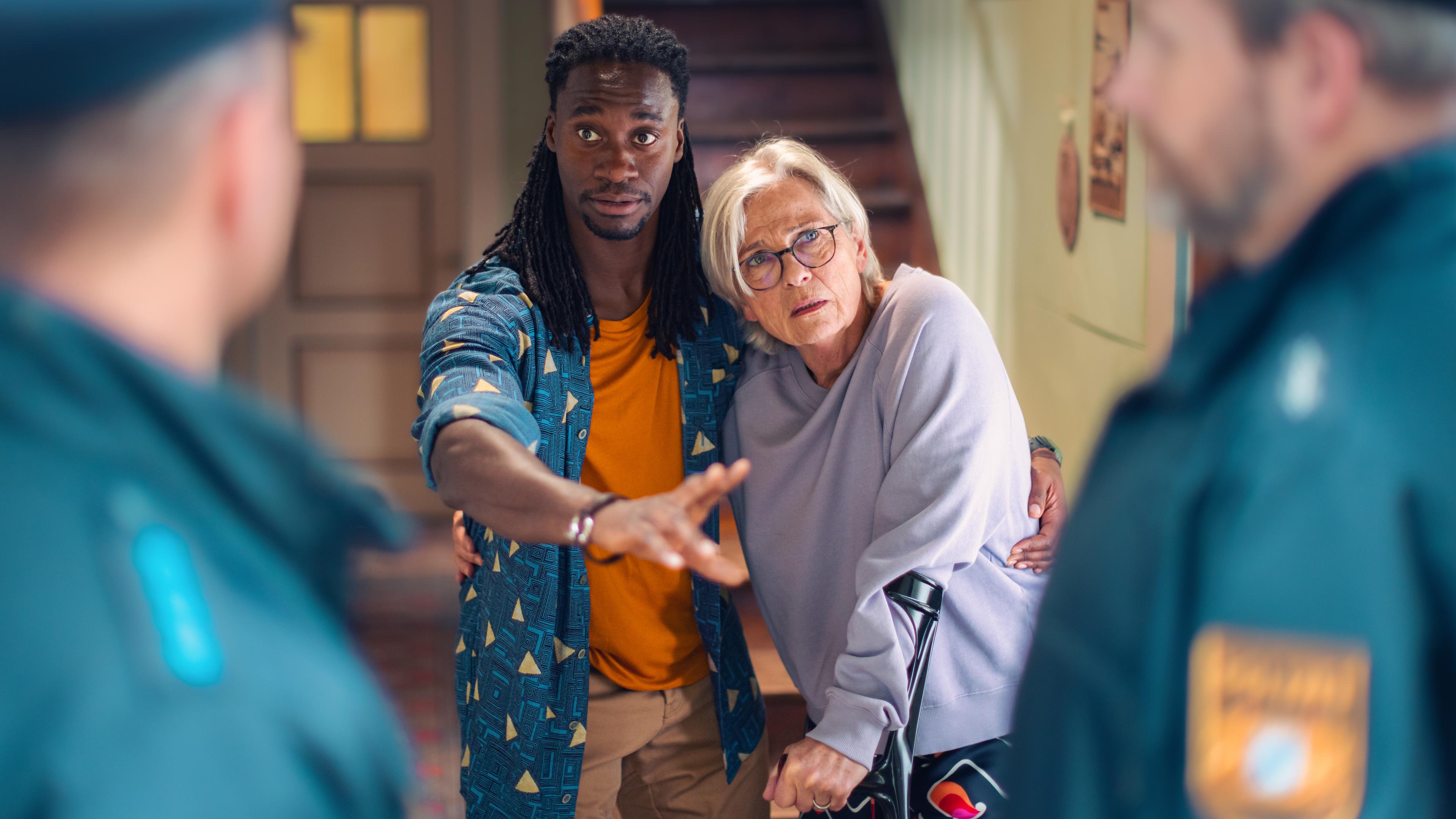 Gerda (Gerburg Jahnke) simuliert einen Schwächeanfall, als sie feststellt, dass Simon (Eugene Boateng) sonst in Schwierigkeiten mit der Polizei kommen könnte.