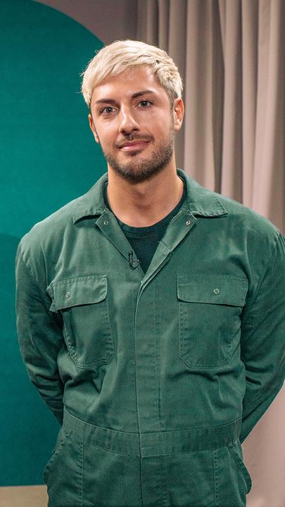 Zwei Männer in grünen Overalls blicken in die Kamera.