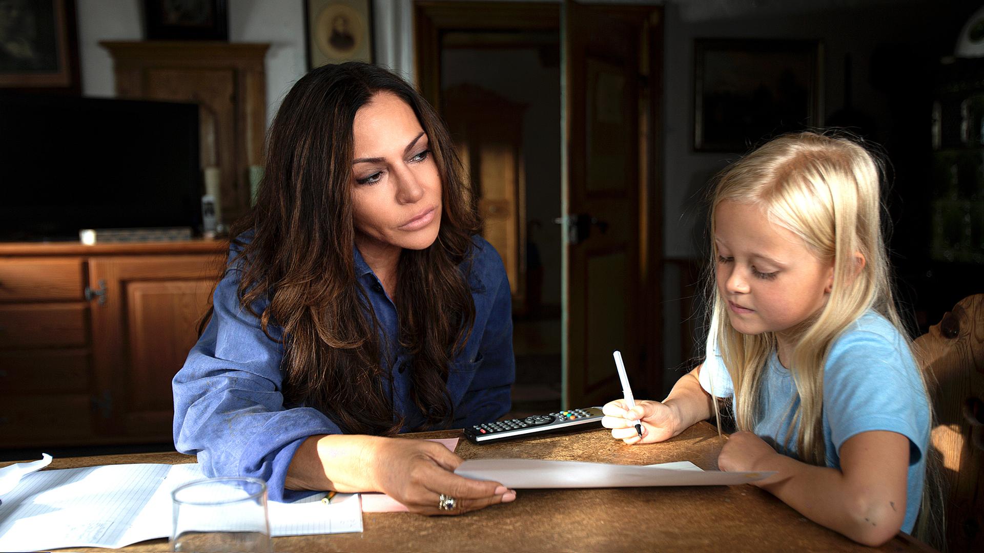 Katja Baumann (Simone Thomalla) sitzt mit Mathilda (Nele Richter) am Tisch und hilft ihr bei den Hausaufgaben.