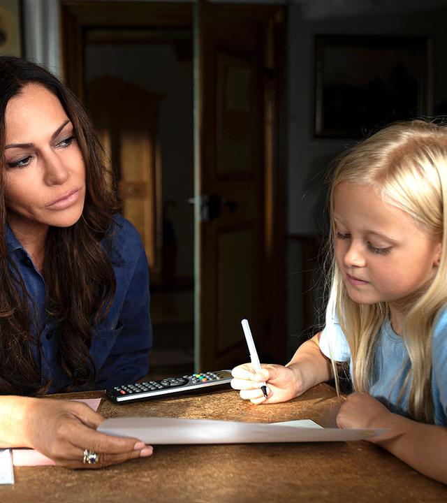 Katja Baumann (Simone Thomalla) sitzt mit Mathilda (Nele Richter) am Tisch und hilft ihr bei den Hausaufgaben.