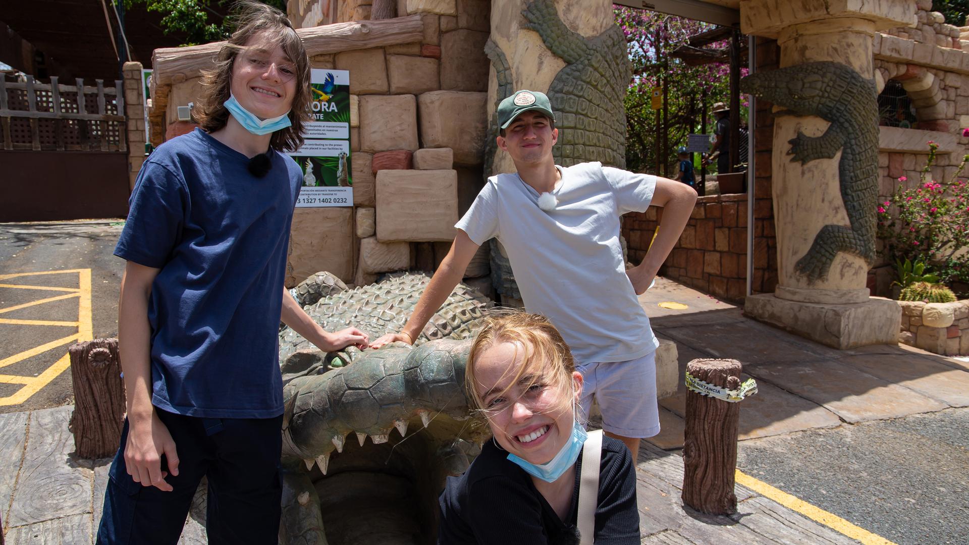 Leo, Lia und Adis stehen vor dem Eingang zu einem Tierpark