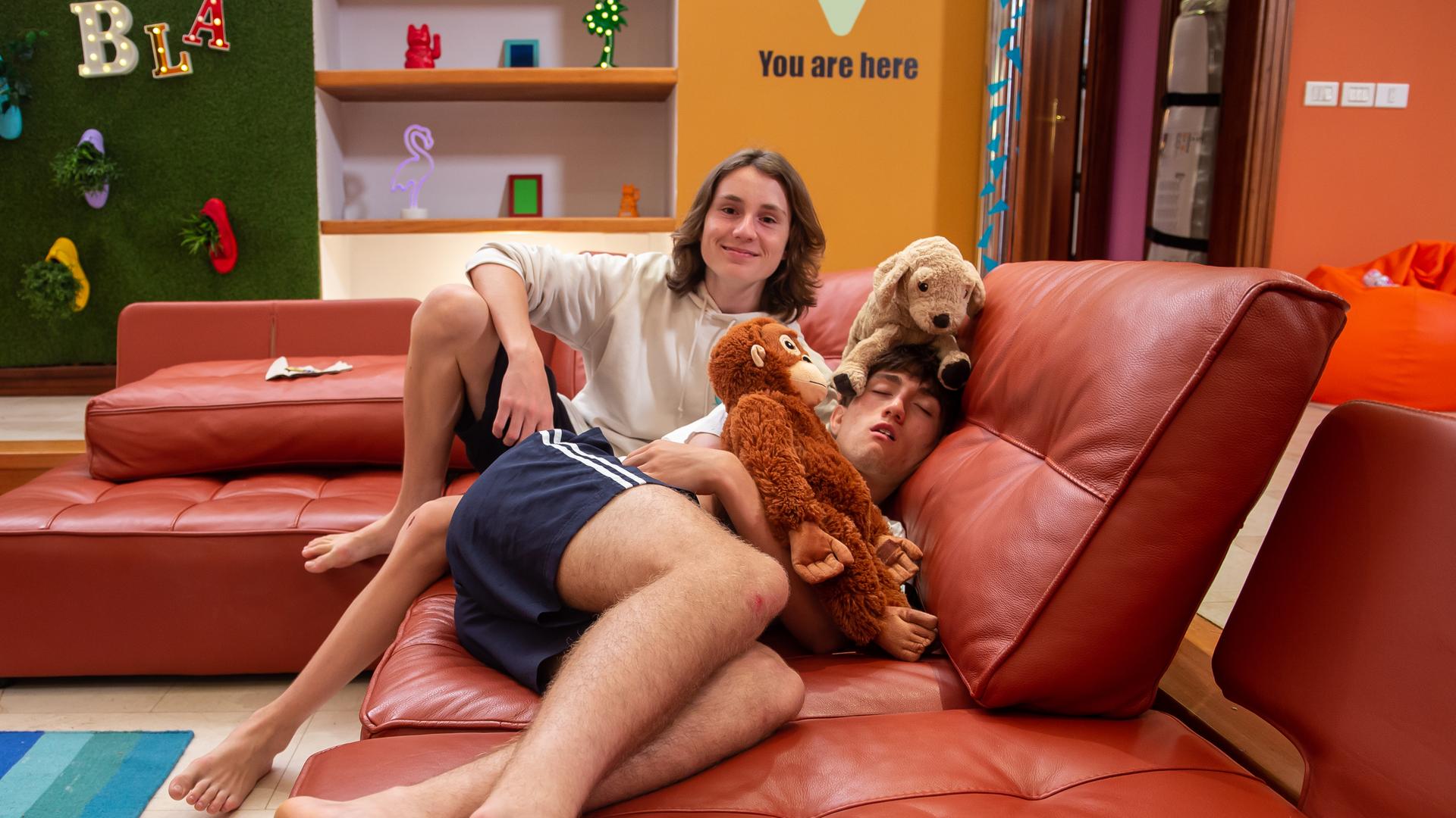 Leo und Adis liegen mit Kuscheltieren auf der Couch