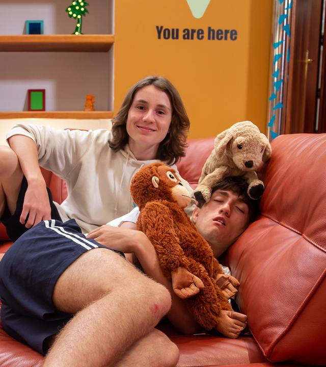 Leo und Adis liegen mit Kuscheltieren auf der Couch