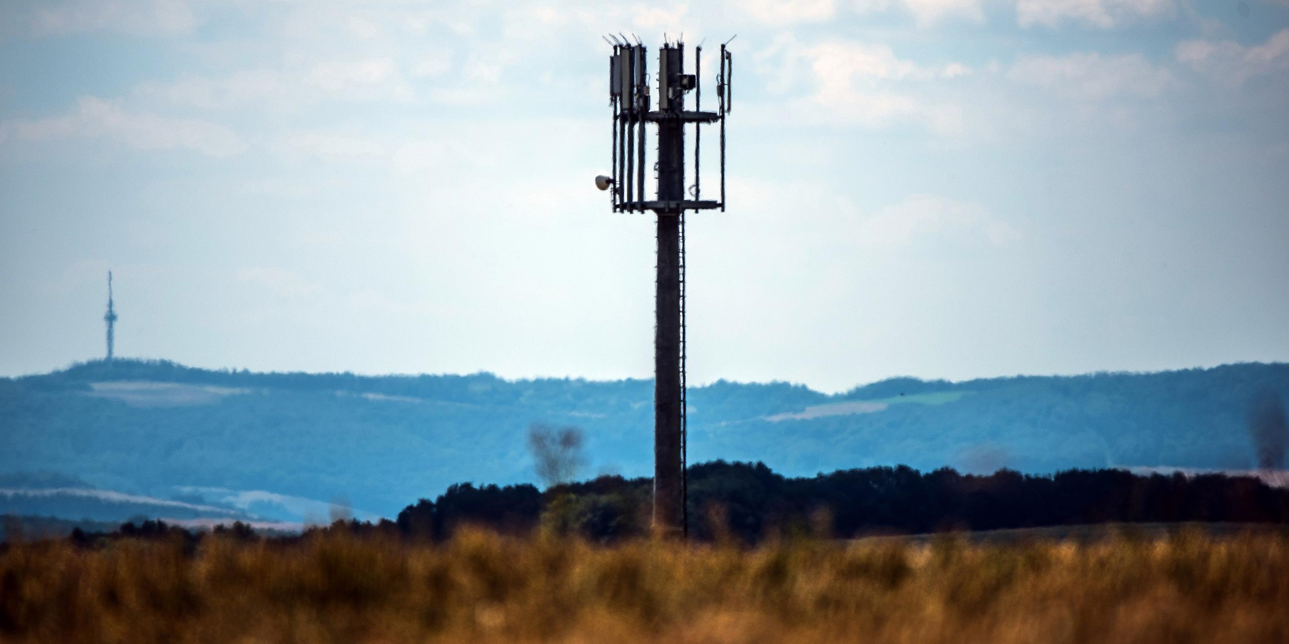 Ein Mobilfunkmast steht auf einer Anhöhe in ländlicher Umgebung