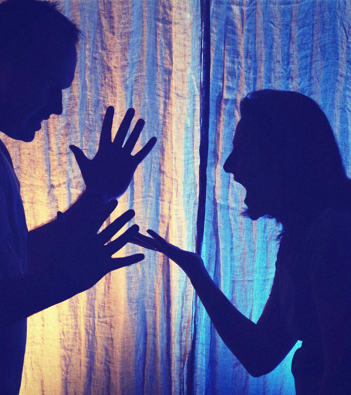 Schattenhafte Aufnahme vor heller Gardine: Die Silhouetten eines streitenden Paares
