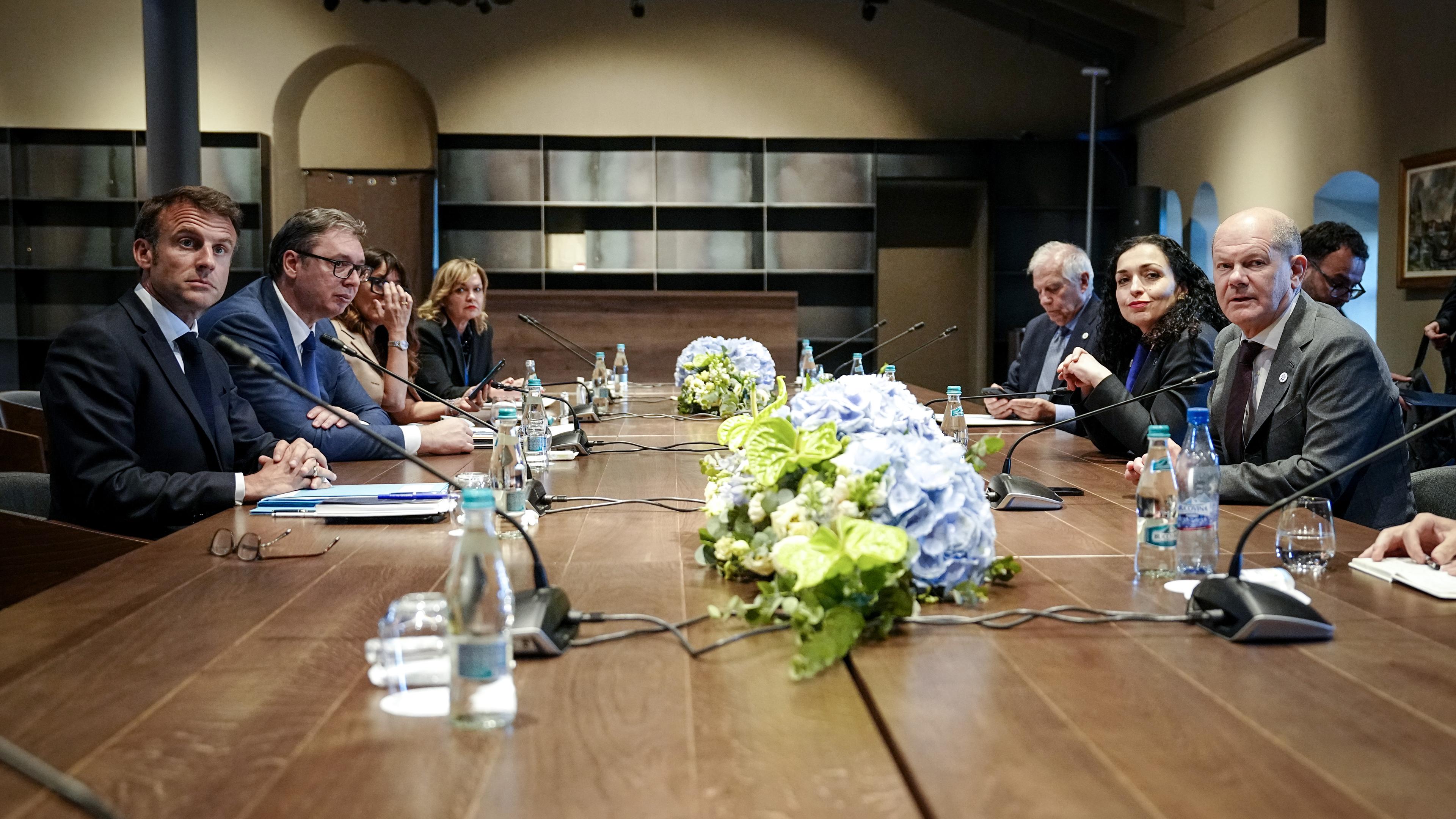 Zu sehen sind europäische Regierungschefs - darunter Macron und Scholz - an einem Konferenztisch in Moldau. In der Tischmitte liegen Blumen. 