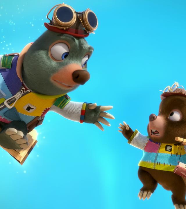 Moley schwebt auf seinem magischen Buch Mauli sitzend am Himmel. Gleich neben ihm hängt der kleine Maulwurfjunge Streusel an Luftballons. Er streckt die Hand nach Moley aus und sieht ängstlich aus. Moley versucht nach Streusels Hand zu greifen.