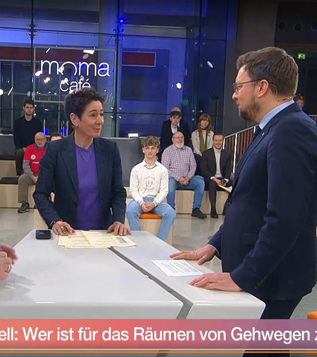 Moderatorin Dunja Hajali zwischen den beiden Studiogästen Roland Stimpel (Fußgängerverband) und Lucas Schaal (Berliner Abgeordnetenhaus) am Moma-Duell-Tisch