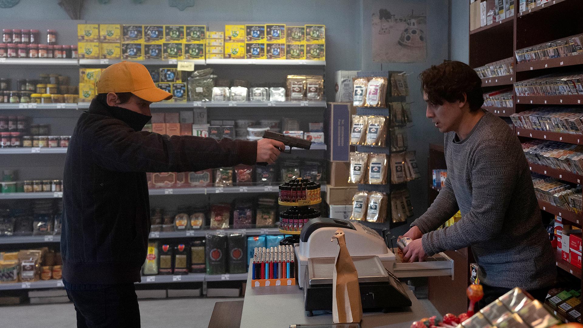 Der vermummte Daniel Kowalski (Joel Basman) fordert mit vorgehaltener Waffen von Damon Merizadi (Yasin Boynuince) sämtliches Geld aus der Ladenkasse.