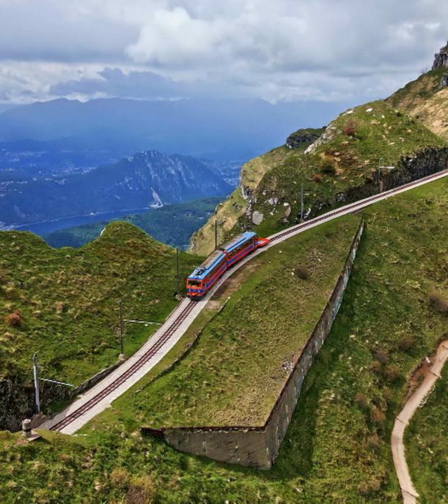 Eine rote Bergbahn unter blauem Himmel auf Bergschienen