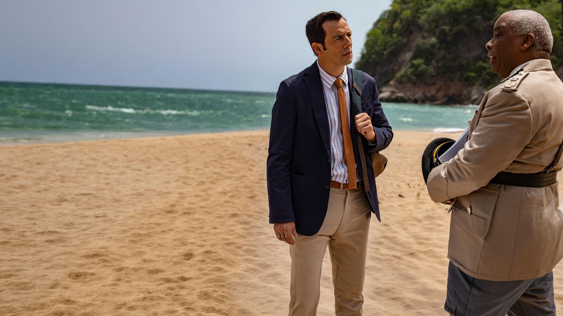 "Death in Paradise - Mord an Deck": Detective Neville Parker (Ralf Little) und Polizeichef Selwyn Patterson (Don Warrington) stehen sich an einem Strand gegenüber und reden miteinander.