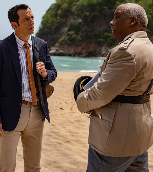 "Death in Paradise - Mord an Deck": Detective Neville Parker (Ralf Little) und Polizeichef Selwyn Patterson (Don Warrington) stehen sich an einem Strand gegenüber und reden miteinander.