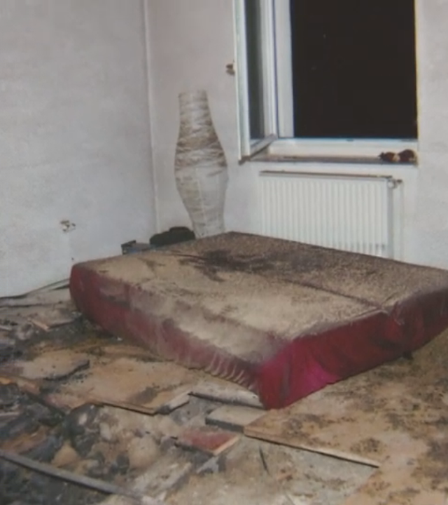 Bild aus der Polizeiakte zeigt Foto einer Brandwohnung. Russspuren, eine Matratze, eine Stehlampe und ein Fenster. Draußen ist es dunkel. Links daneben: Lichtschematische Darstellung eines Fingerabdrucks.