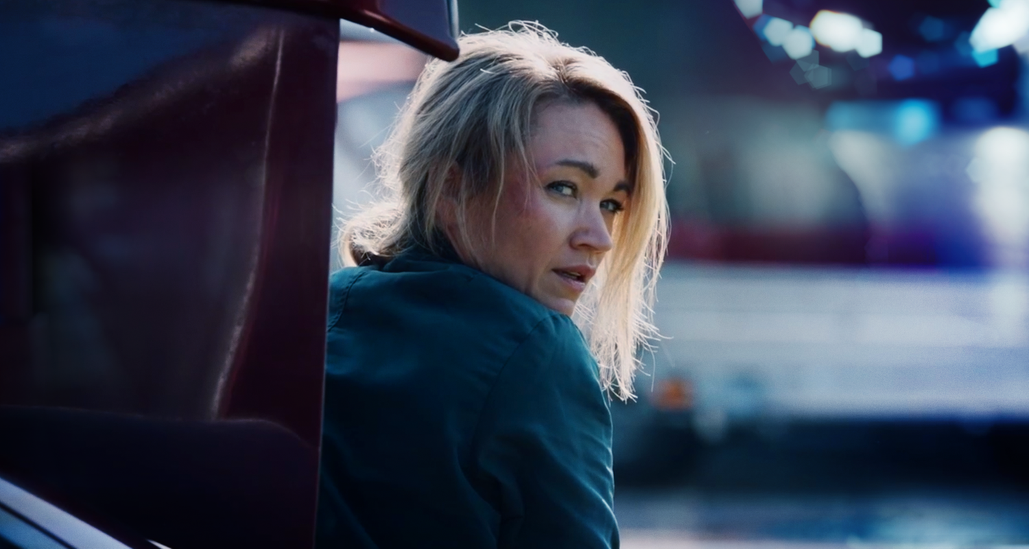 Sarah Kohr (Lisa Marie Potthoff) sitzt mit zerzasuter Frisur und Schramme im Gesicht in einem geöffneten Kofferraum. 