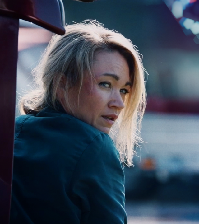 Sarah Kohr (Lisa Marie Potthoff) sitzt mit zerzasuter Frisur und Schramme im Gesicht in einem geöffneten Kofferraum. 