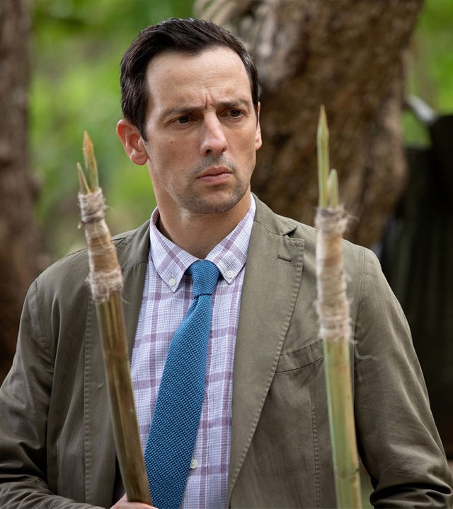 "Death in Paradise - Mosquito Island": Detektive Neville Parker (Ralf Little) schaut konzentriert auf zwei Speere.