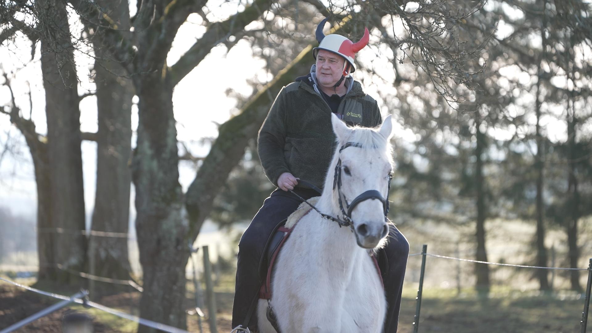 Waldi sitzt auf einem Pferd.