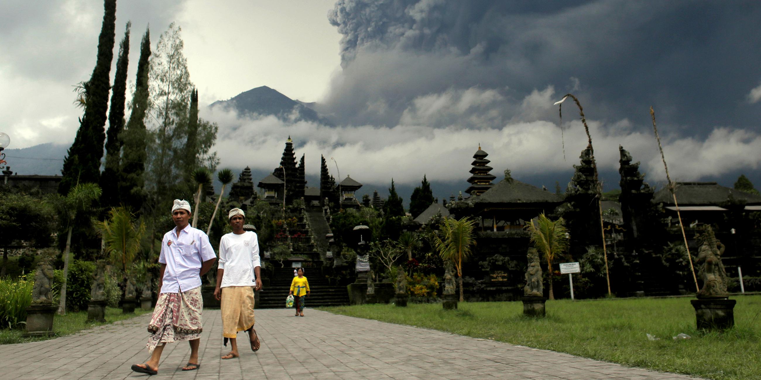 Zwei Hindus im Besakih Tempel auf Bali, im Hintergrund der Mount Agung am 26.11.2017