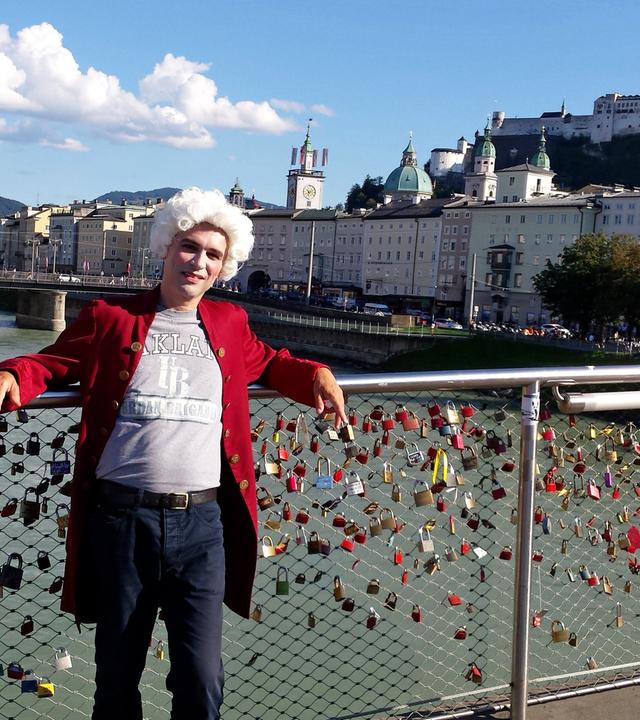 Ein junger Mann in Salzburg auf einer Brücke stehend, als Mozart verkleidet.