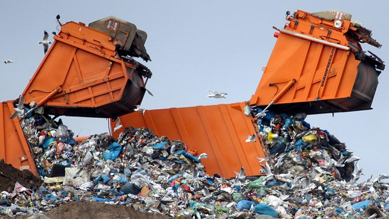 Zwei Müllautos laden auf einer Mülldeponie Abfall ab