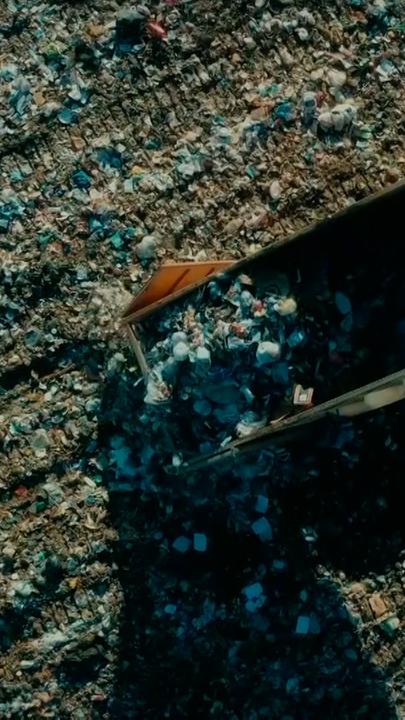 Ein Laster von oben, der Müll ablädt. Um ihn herum liegt bereits sehr viel Müll.