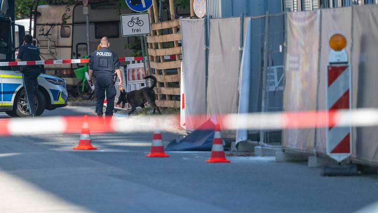  Ein Polizist mit einem Polizei-Spürhund läuft an einem Firmengelände vorbei. 
