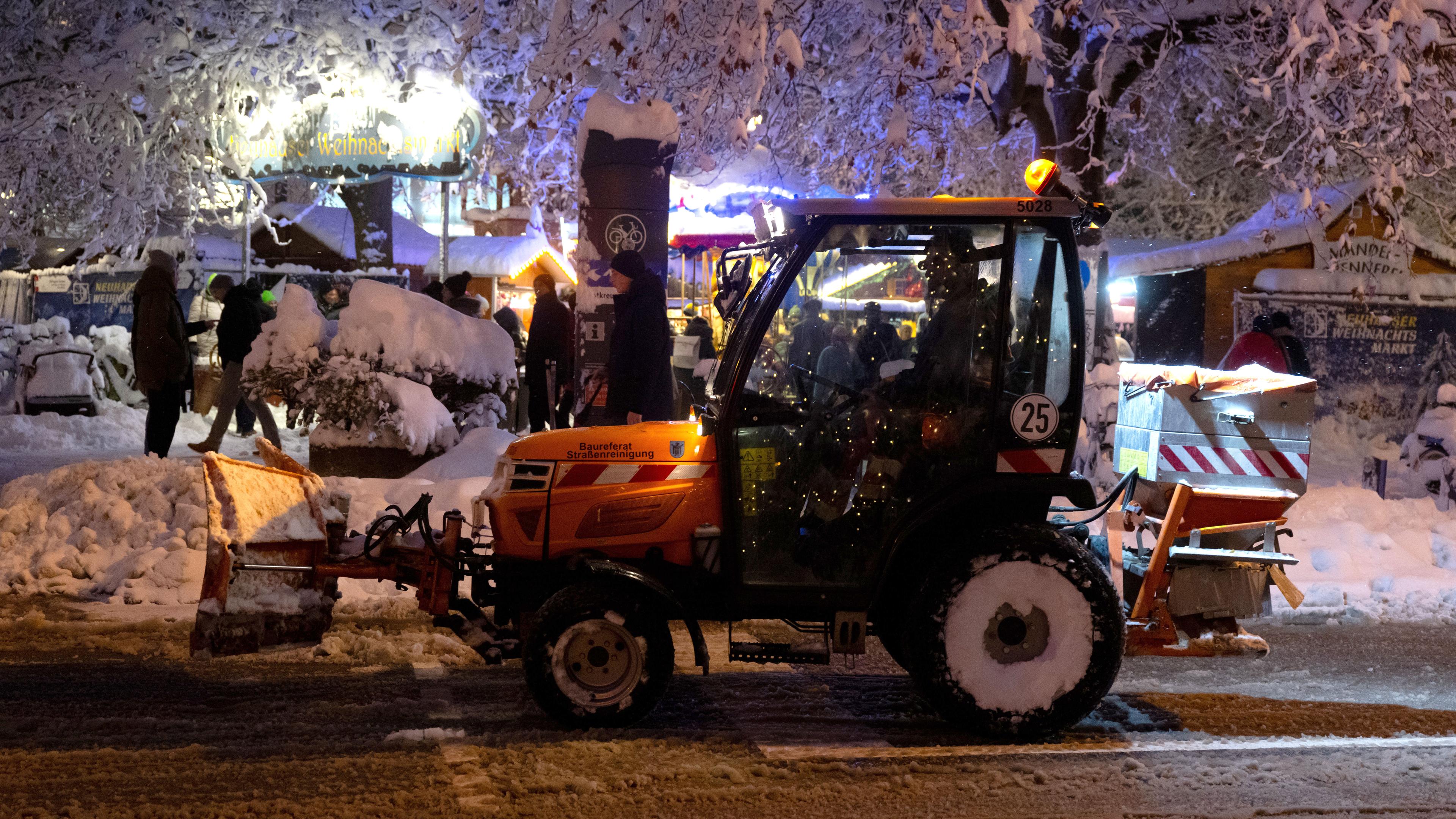 Ein Schneepflug räumt die Straße vor einem Weihnachtsmarkt am Rotkreuzplatz in München