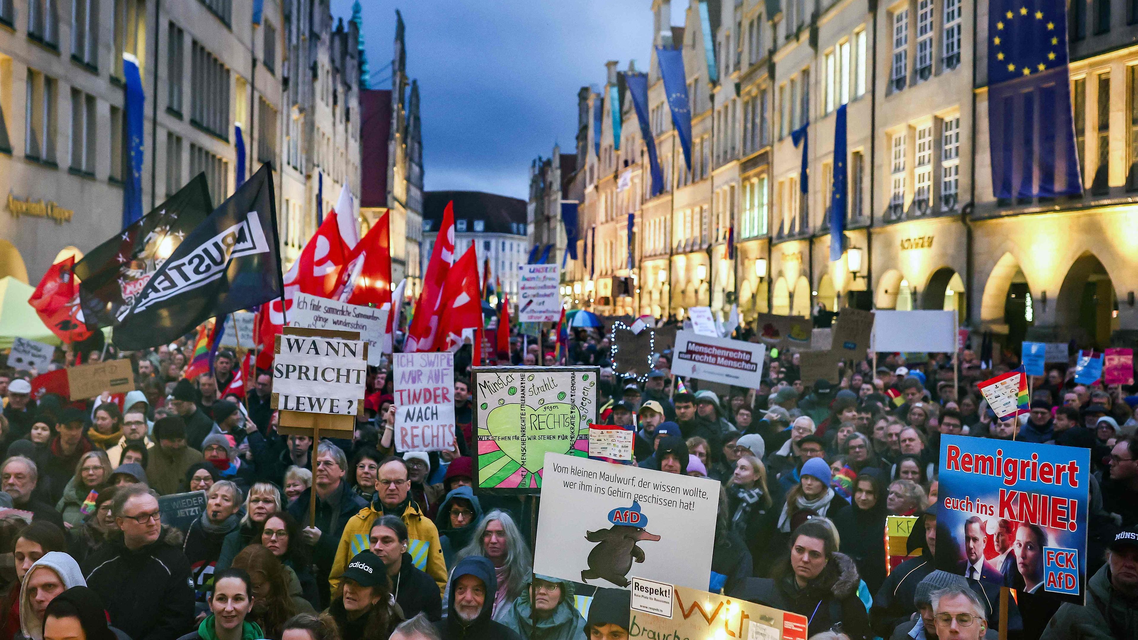 Menschen laufen durch die Innenstadt von Münster mit Plakaten gegen Rechtsextremismus und die AfD. 