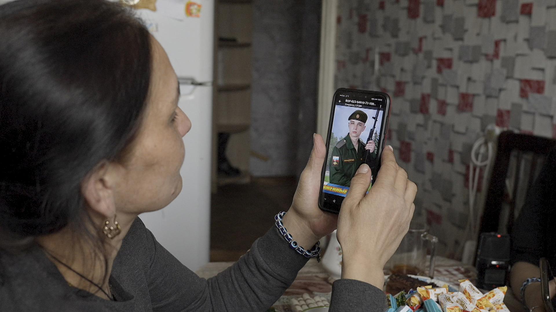 Mutter eines russischen Soldaten schaut sich Foto ihres Sohnes auf dem Handy an.