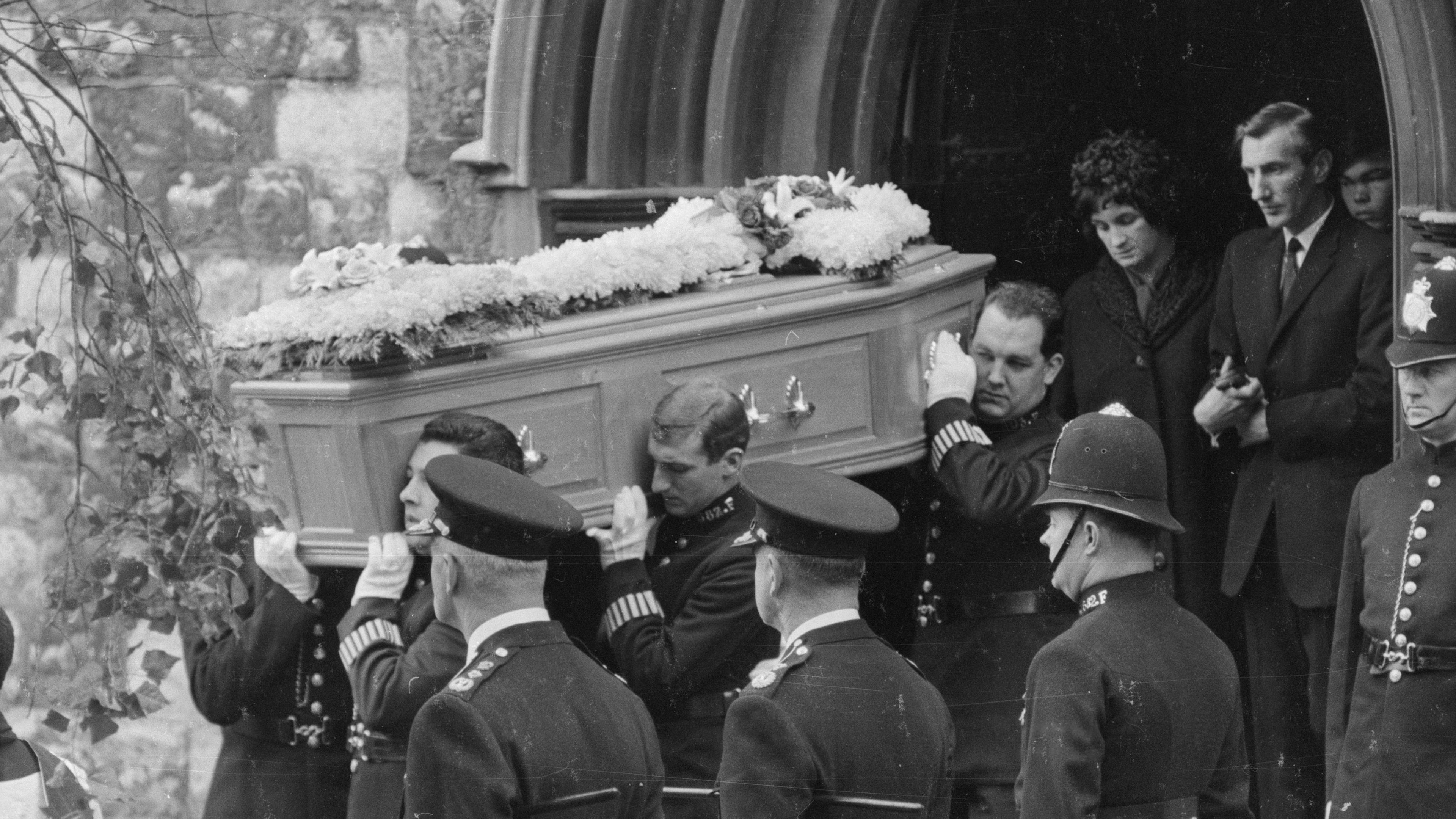 "Murder Maps - Geheimnisvolle Verbrechen: Polizistenmord in London": Schwarz-Weiß-Aufnahme: Bei der Beerdigung der getöteten Polizisten tragen schwarz gekleidete Männer einen Sarg aus der Kirche.