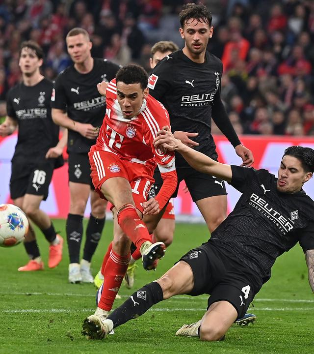 Gladbachs Verteidiger Kevin Diks grätscht im Zweikampf in Bayerns offensiven Mittelfeldspieler Jamal Musiala rein