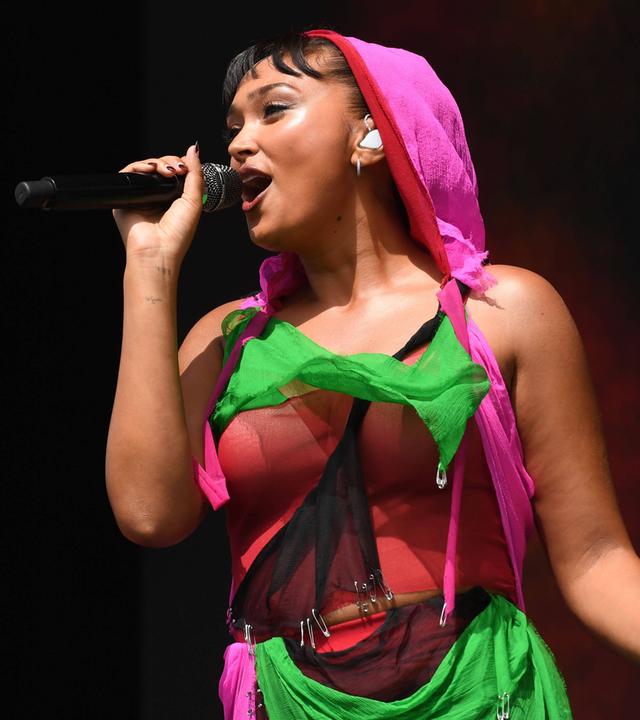 Eine Frau in einem bunten Kostüm singt in ein Mikrofon.