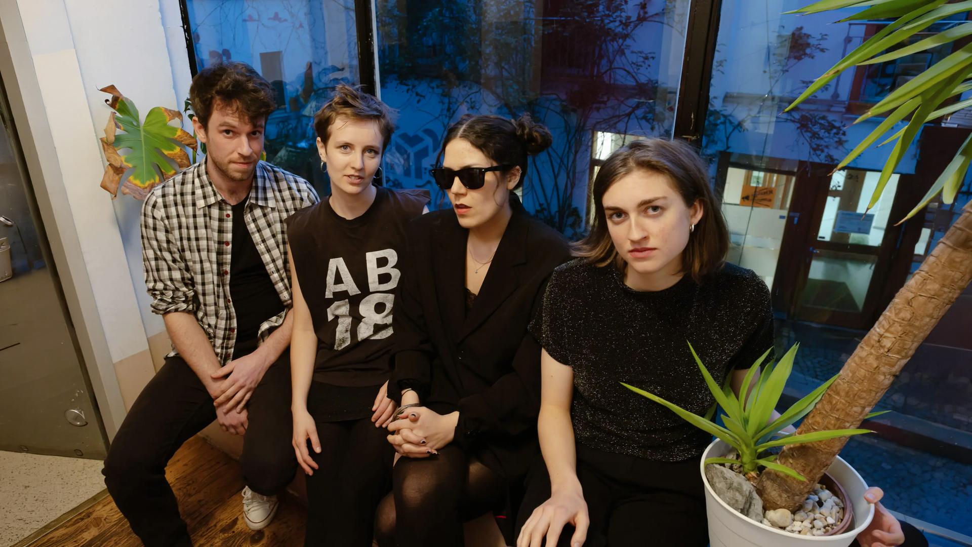Ein Mann und drei Frauen sitzen vor einem Fenster.