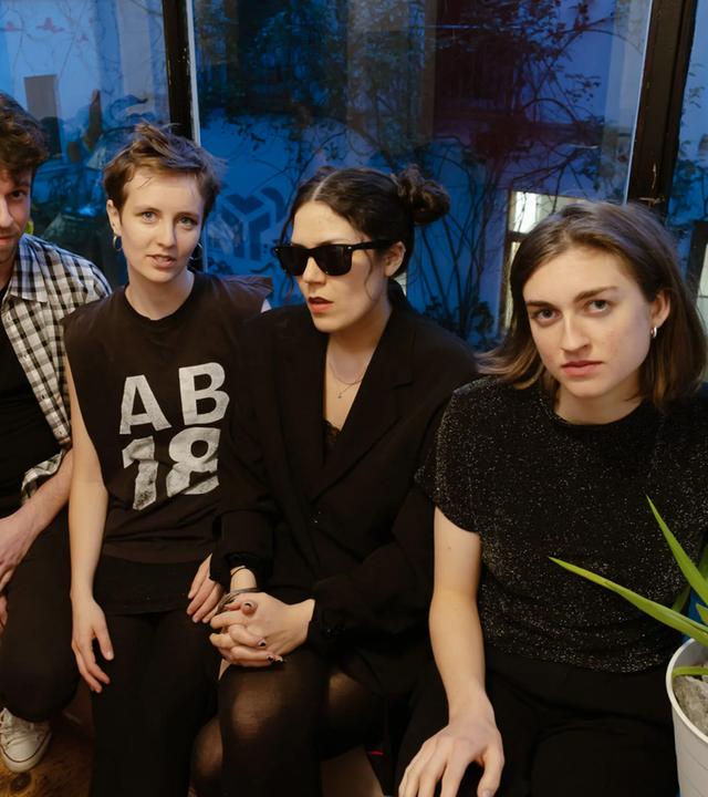 Ein Mann und drei Frauen sitzen vor einem Fenster.