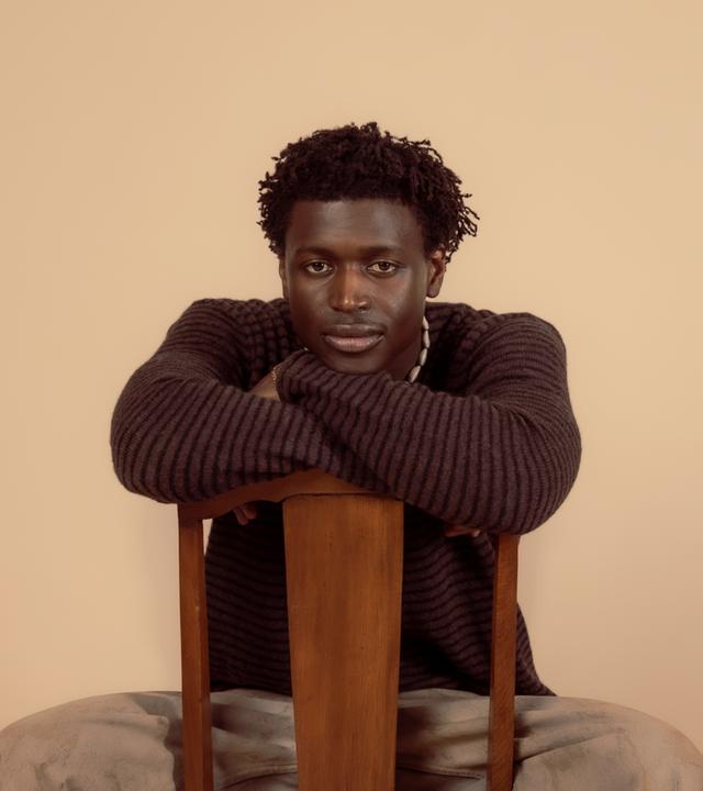 Man sieht einen Mann der auf einem Stuhl sitzen.