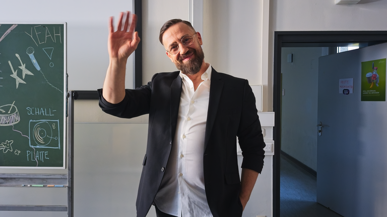 Bürger Lars Dietrich  in Sakko winkt in die Kamera.
