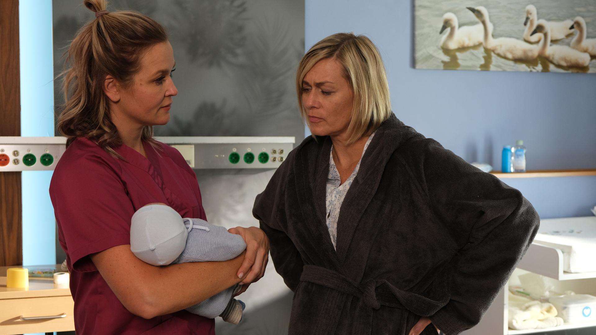 "Lena Lorenz - Mutterliebe": In einem Krankenzimmer stehen sich Lena Lorenz (Judith Hoersch) und Petra Hoffmann (Gesine Cukrowski) gegenüber und sprechen miteinander. Lena hält ein Baby im Arm.