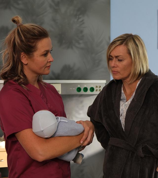 "Lena Lorenz - Mutterliebe": In einem Krankenzimmer stehen sich Lena Lorenz (Judith Hoersch) und Petra Hoffmann (Gesine Cukrowski) gegenüber und sprechen miteinander. Lena hält ein Baby im Arm.