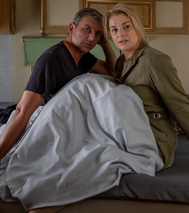 Martin (Hans Sigl) und Anne (Ines Lutz) sitzen unter Decken im Bett eines Wohnmobils. Beide blicken verwirrt.