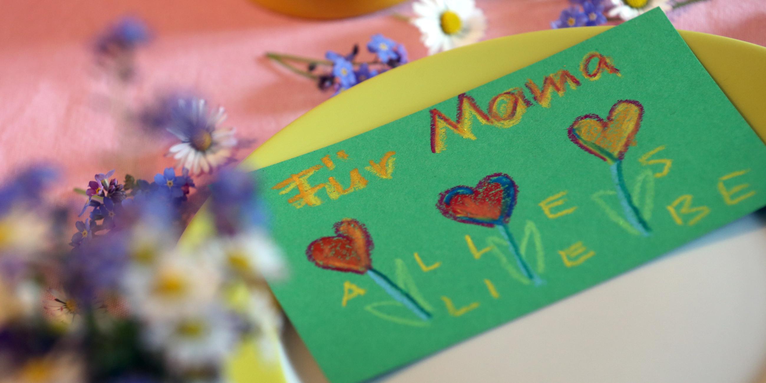 Eine selbstgemalte Muttertagskarte und Blumen