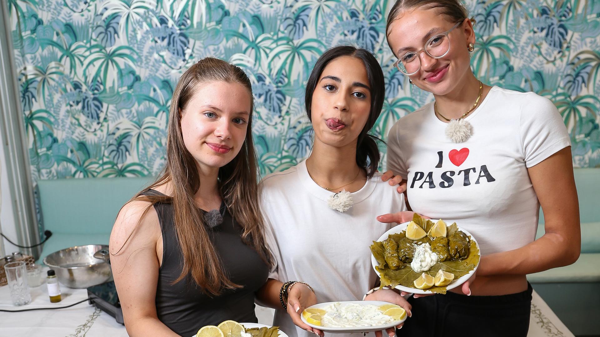 Josefine, Mahak und Nele haben gekocht und präsentieren das fertige Essen in der Küche.