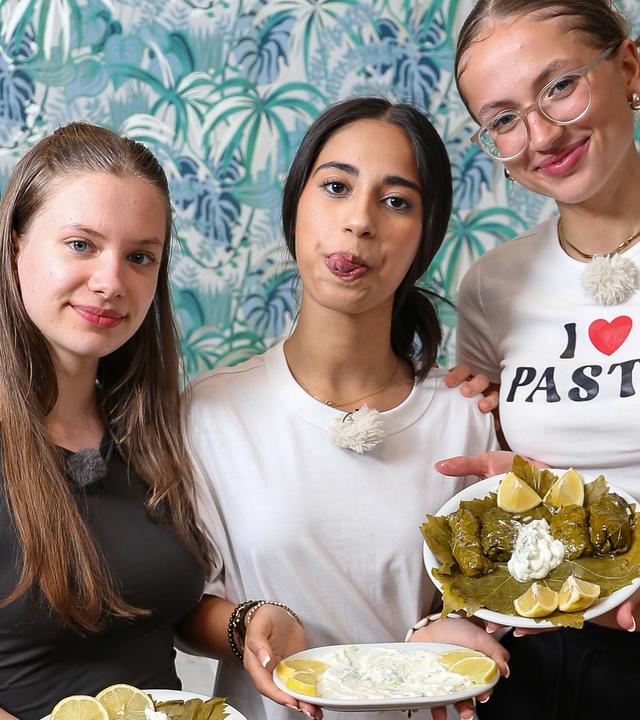 Josefine, Mahak und Nele haben gekocht und präsentieren das fertige Essen in der Küche.