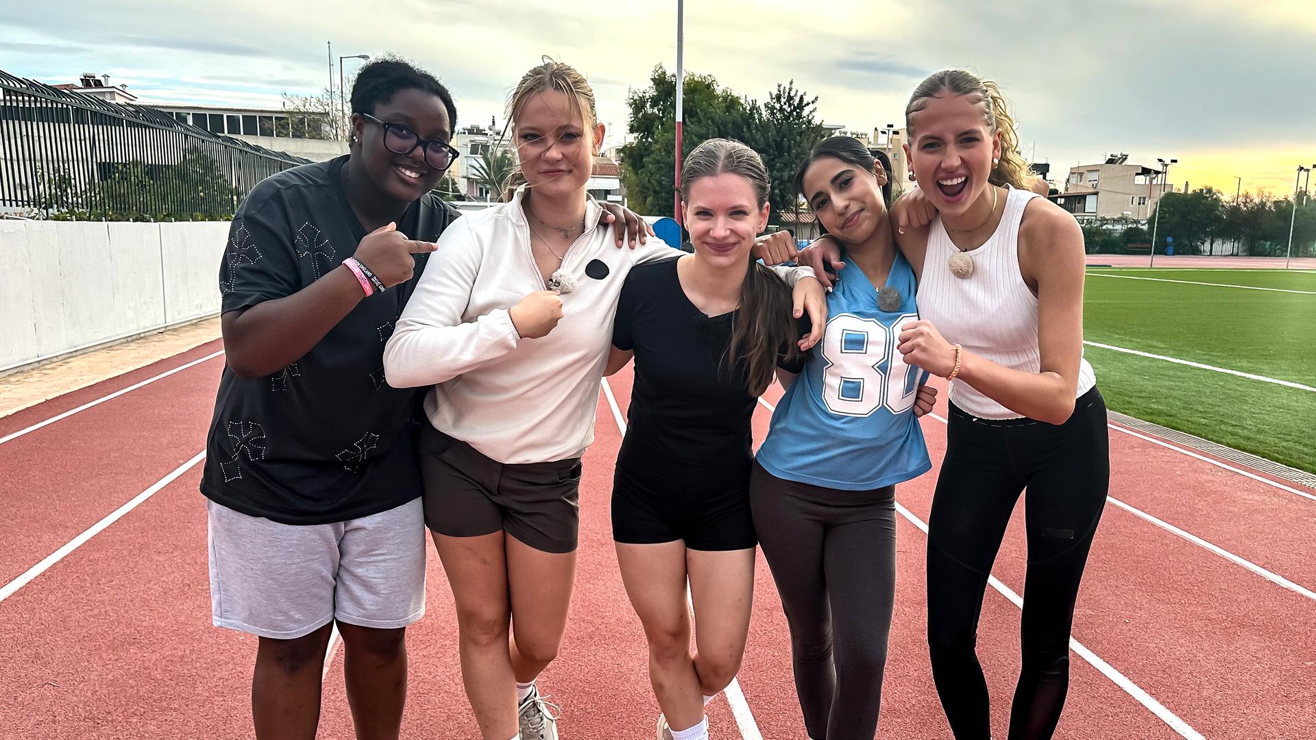 Faith, Johanna, Josefine, Mahak und Nele stehen stolz auf der Laufbahn eines Sportplatzes.
