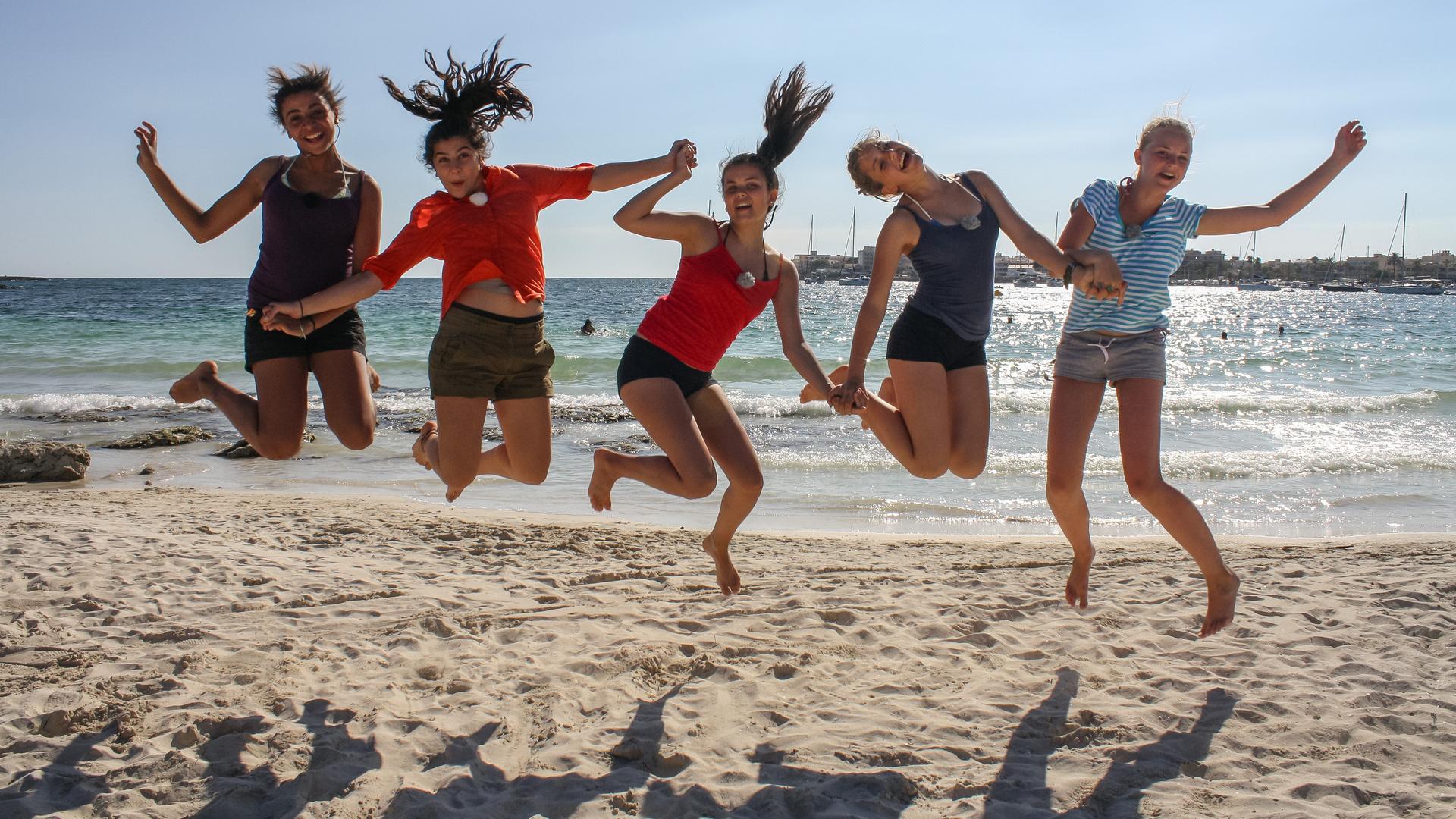 Die Mädchen aus der Mallorca-WG springen am Strand in die Luft und halten sich an den Händen. V.l.n.r.: Bianca, Buse, Louisa, Weya, Maja