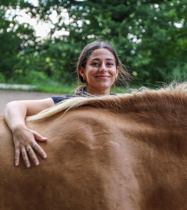 Feli schaut über den Rücken eines Pferdes