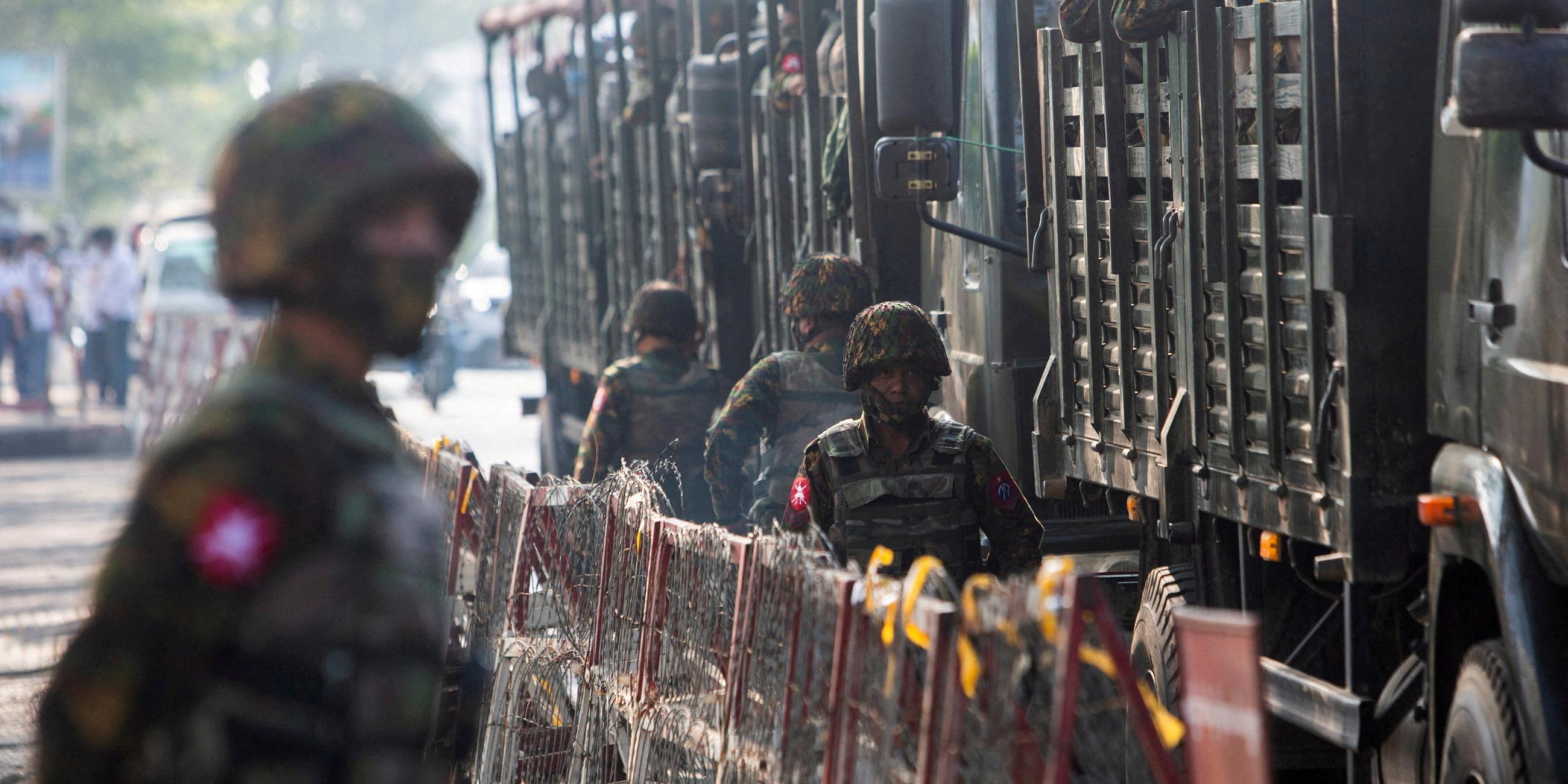 Soldaten des myanmarischen Militärs stehen bei einer Demonstration neben einem Militärfahrzeug.
