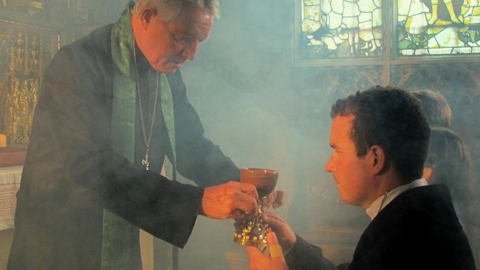 "Mythen-Jäger: Der Kelch von Valencia": Filmszene: Priester gibt die Heilige Kommunion mit dem Kelch von Valencia.