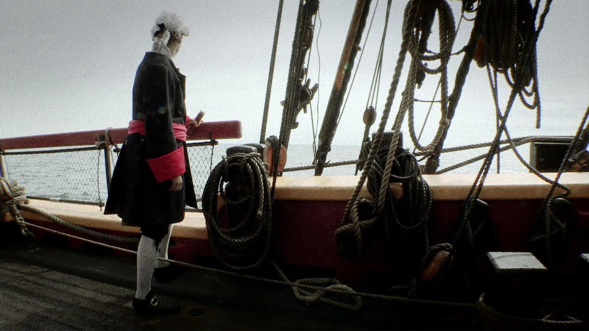 "Mythen-Jäger: Der Piratenschatz des Capttain Kidd": Ein Mann steht auf einem Schiff und blickt in die Ferne. Er hat ein Fernrohr in der Hand, blickt jedoch nicht durch.