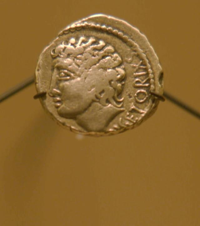  Eine Goldmünze mit dem Portrait eines jungen Mannes. Die Buchstaben "GETORIX" sind noch zu erkennen. Am rechten und linken Bildrand sind zwei weitere Münzen abgebildet, die weniger gut erhalten sind.